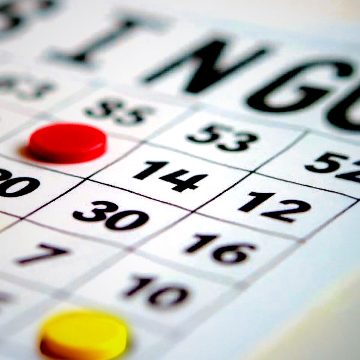 Corner of a bingo board with red and yellow markers over some of the numbers.