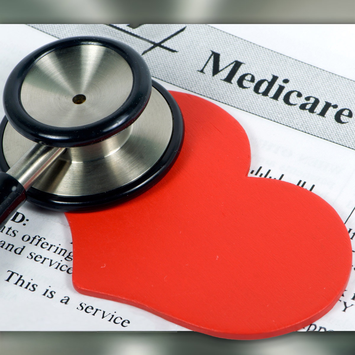 Image shows some paperwork labeled, "medicare" with a red cut-out heart and one end of a stethoscope sitting on the paperwork.
