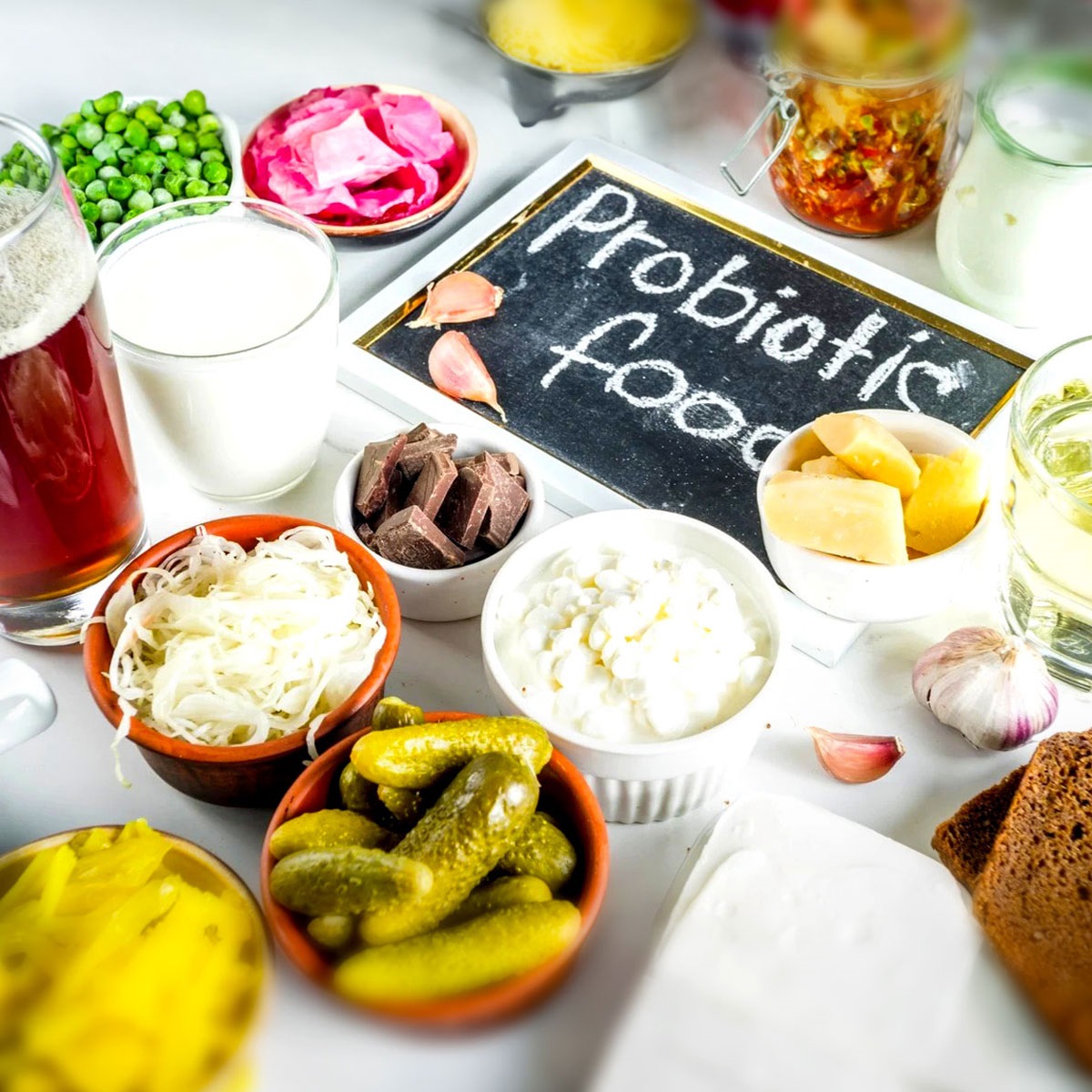 Image shows a smattering of probiotic foods -- pickled vegetables, yogurt, etc.  There is a chalkboard in the middle of all the food reading, "probiotic foods."