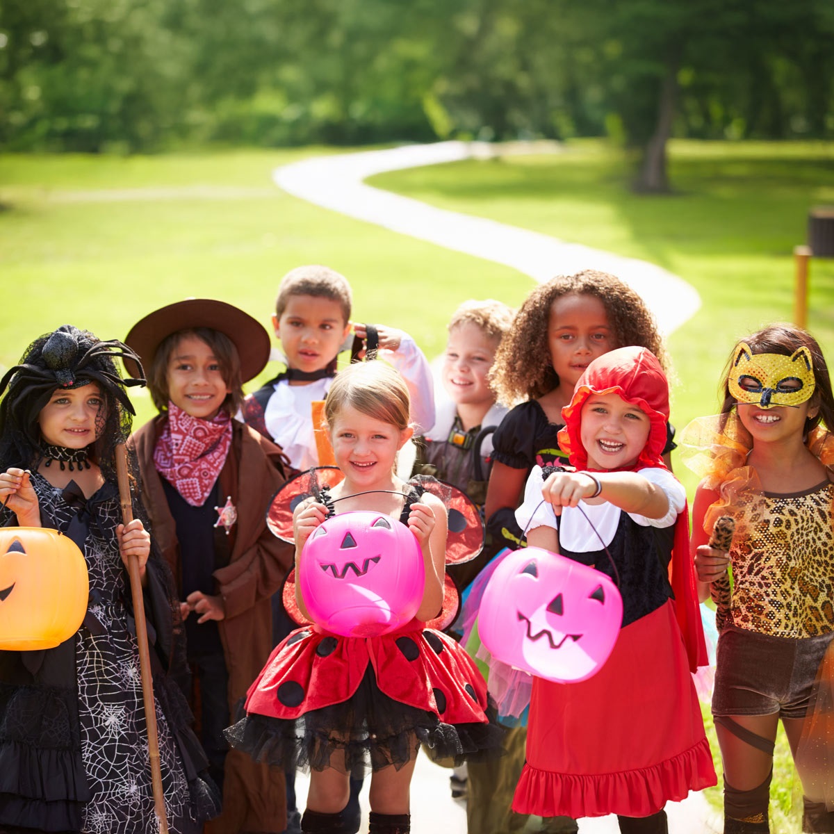Several children dressed up in costumes holding jack-o-lantern shaped buckets.