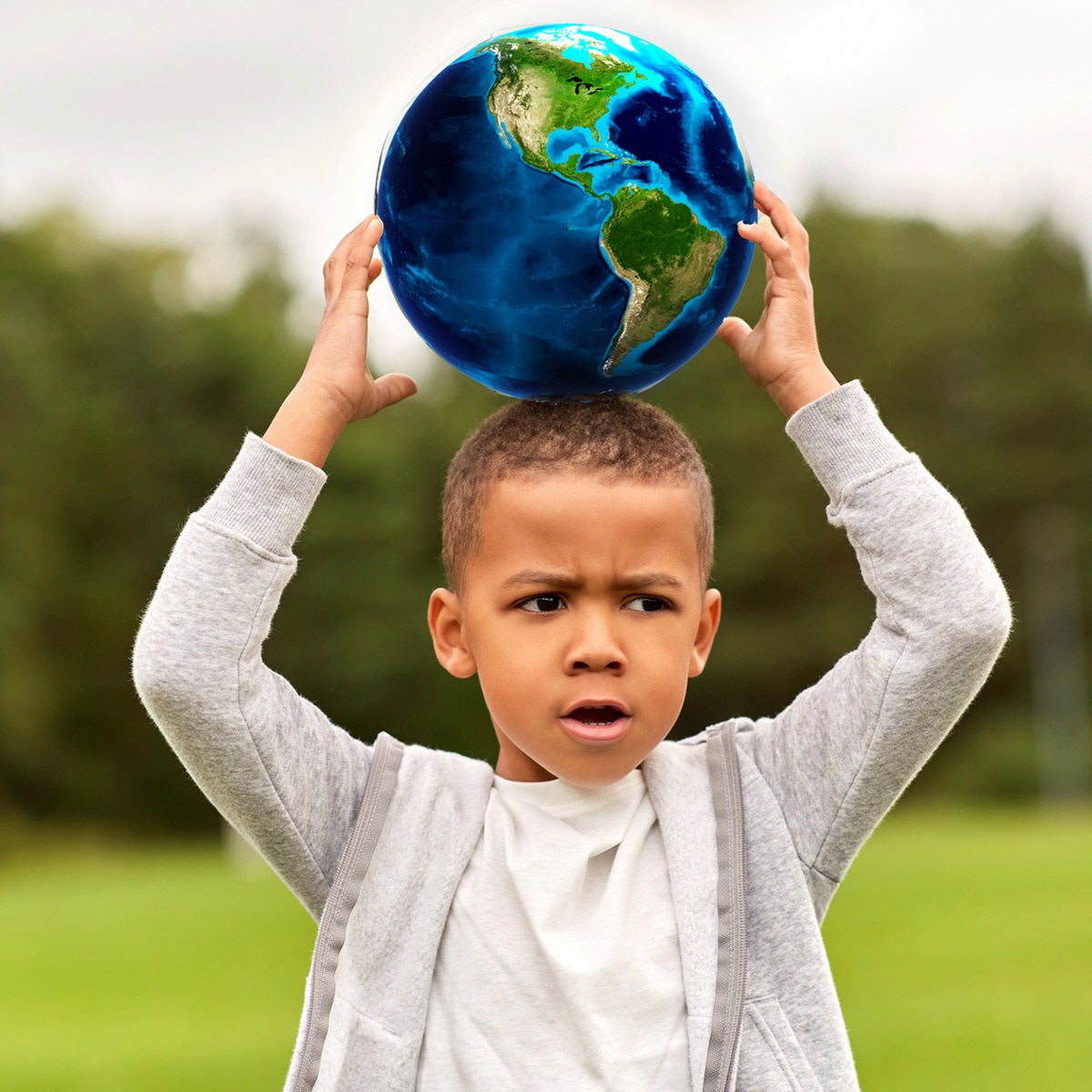 Boy holding a globe above his head.