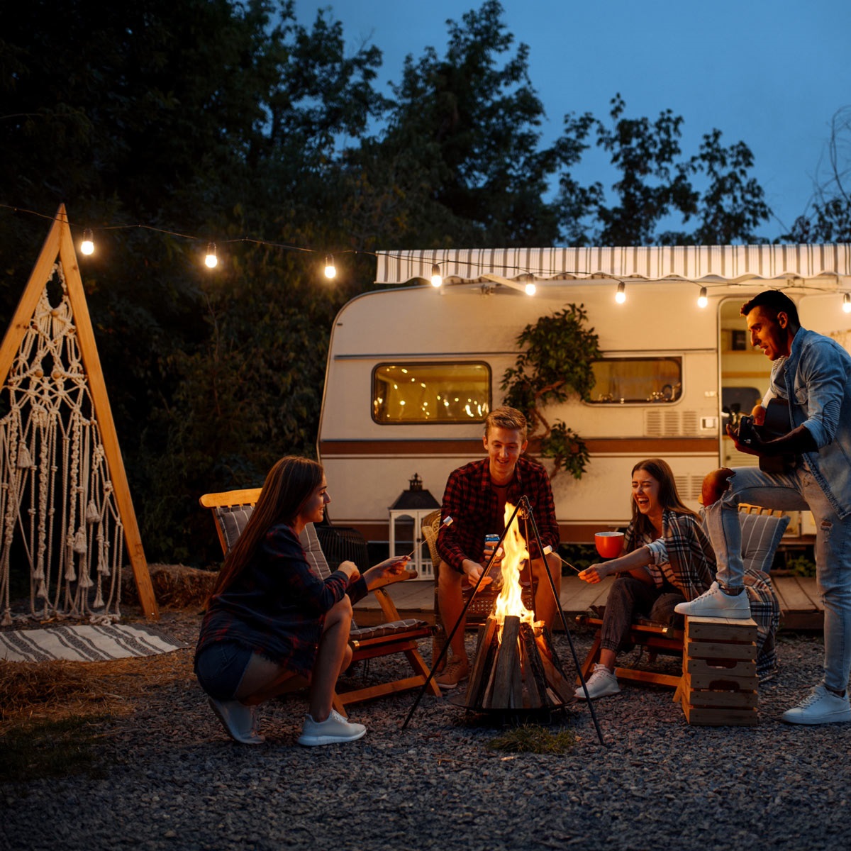 Campers around a campfire in front of an older looking RV.
