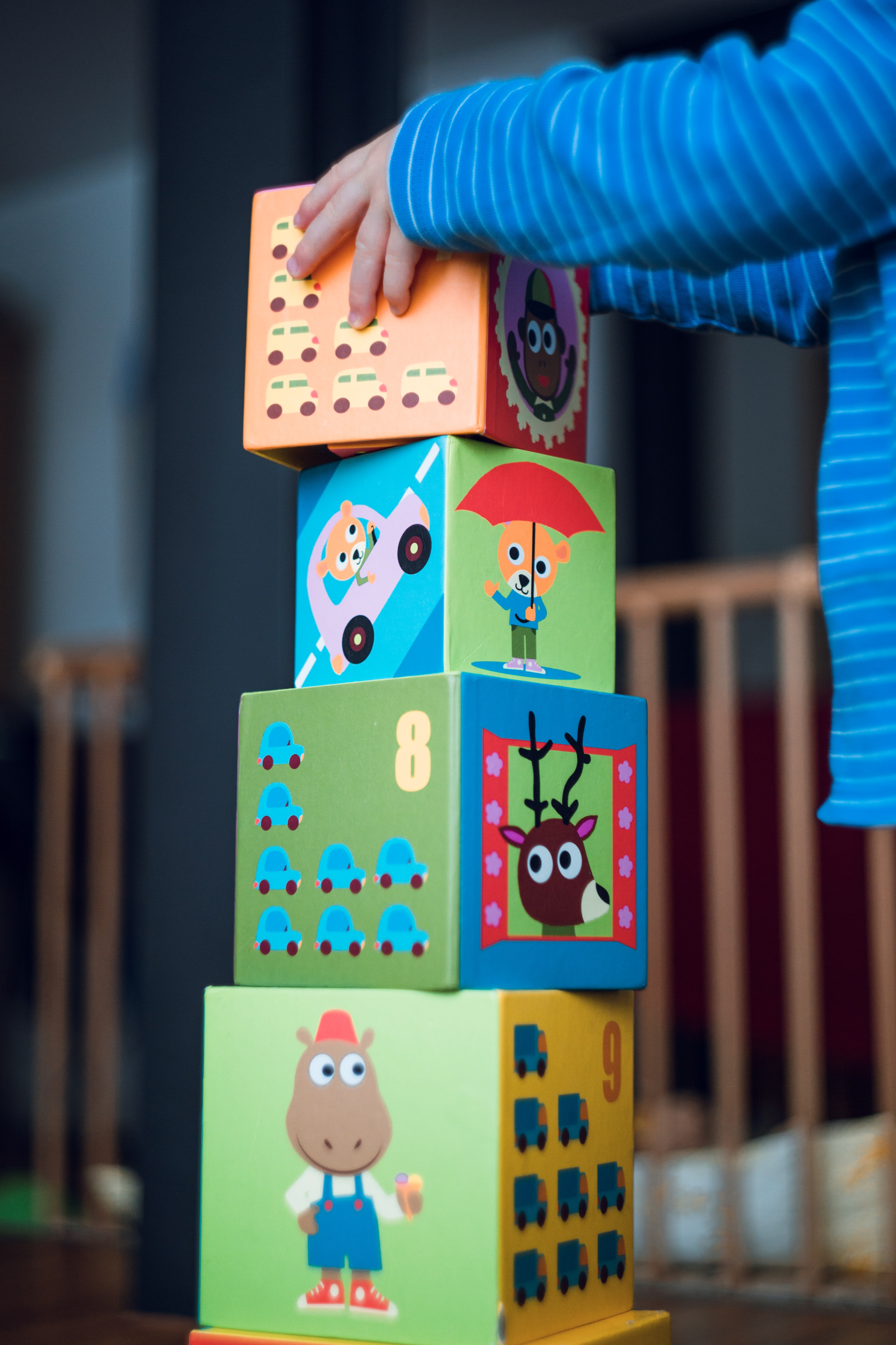 stack of four large blocks and a child's hands placing block on top