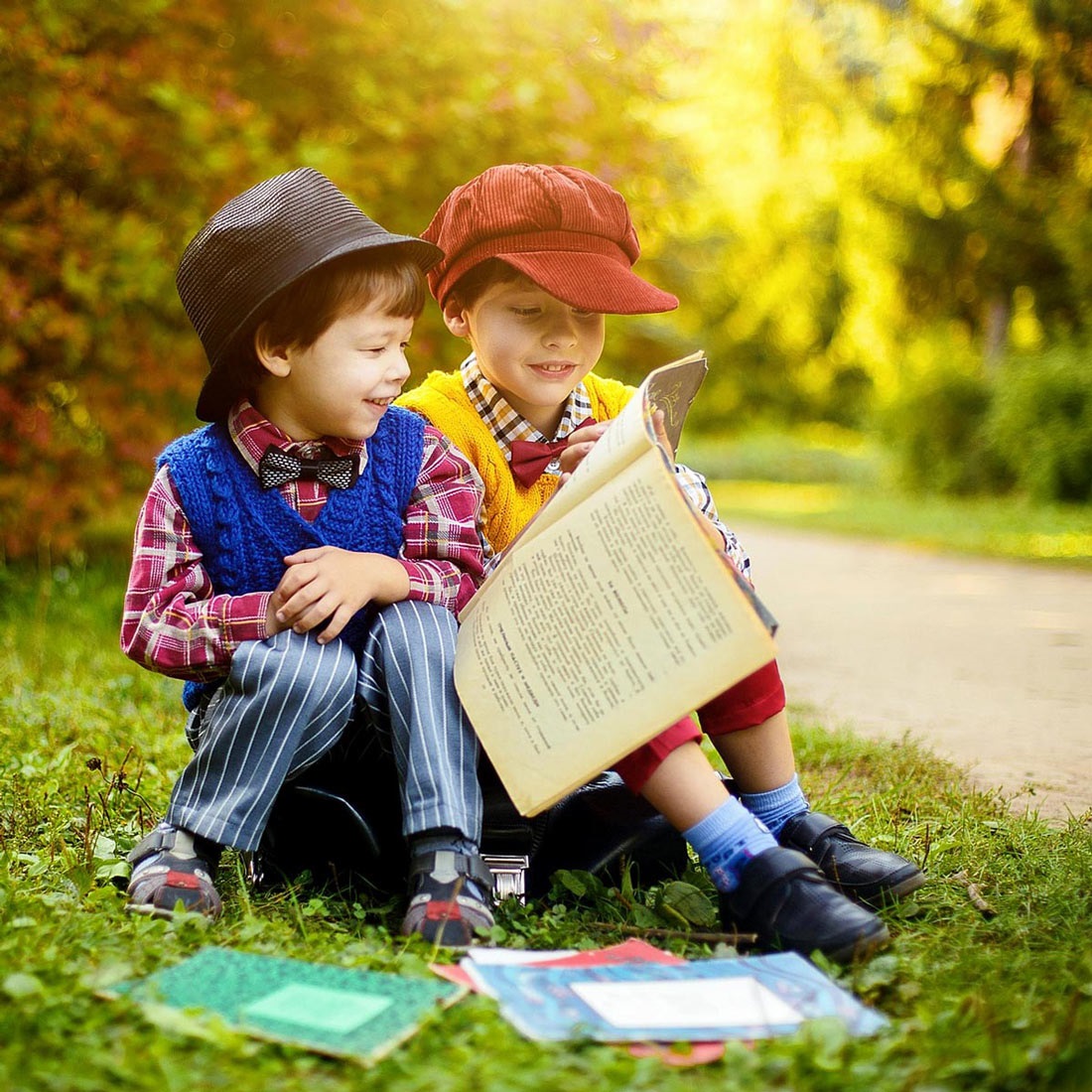 Two curious kids sitting in the forest and reading a book about nature.