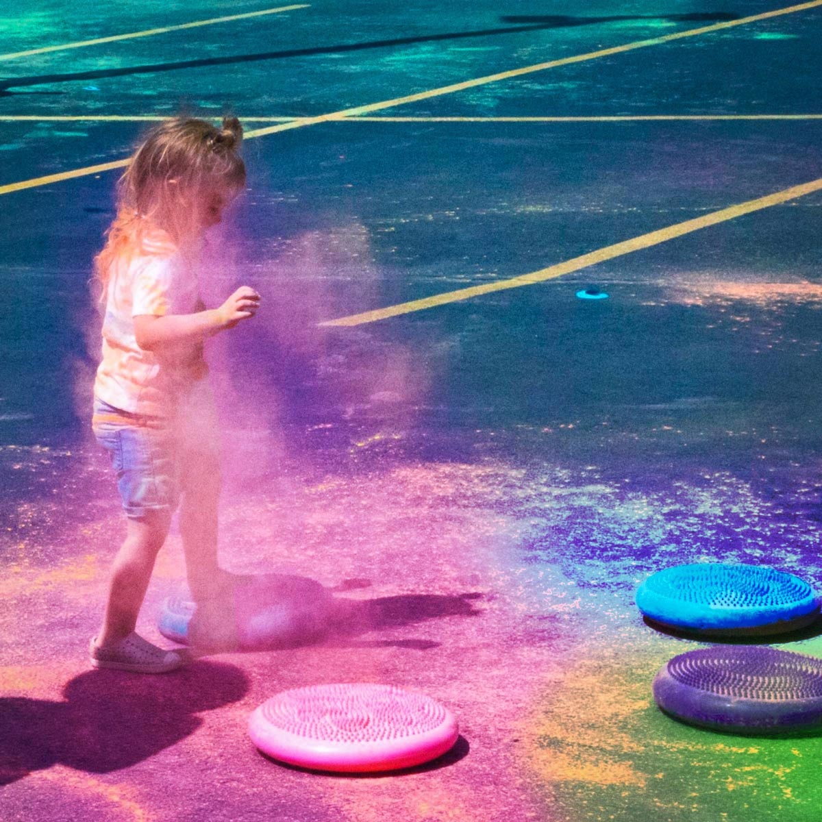 A little girl, stomping on walking pads loaded with colorful chalk, for the Ty-Ran-Asaurus Rex Color Stomp.