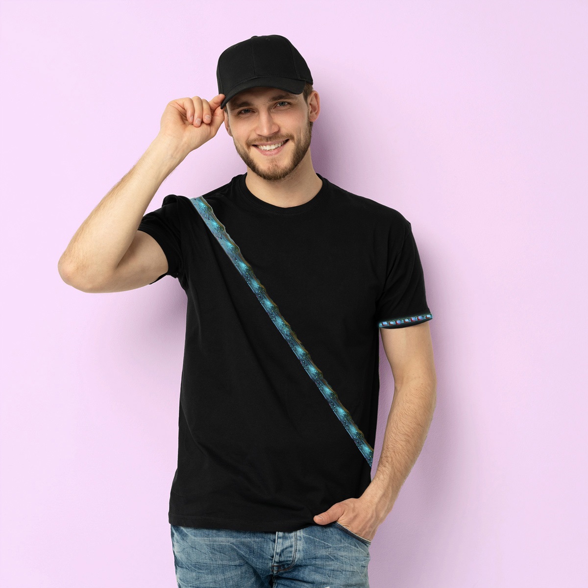 Pic depicts a man in blue jeans, a black t-shirt, and a black hat.  Across his shirt is a glowing sash.