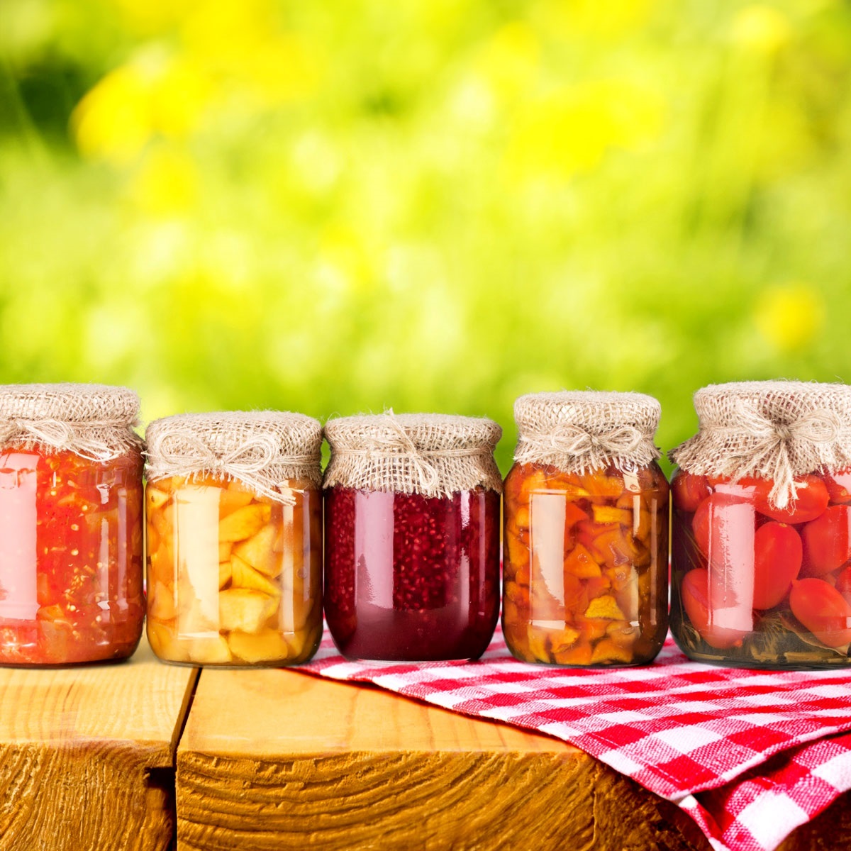 Image depicts 5 jars of pickled or preserved vegetables in a rainbow of colors. 