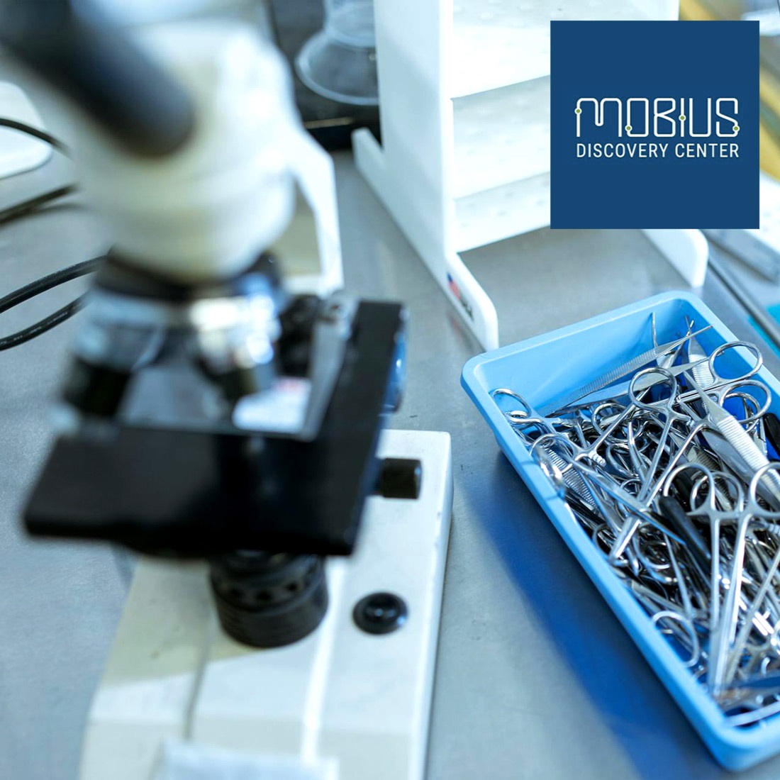 A microscope and lab tools with the Mobius logo.