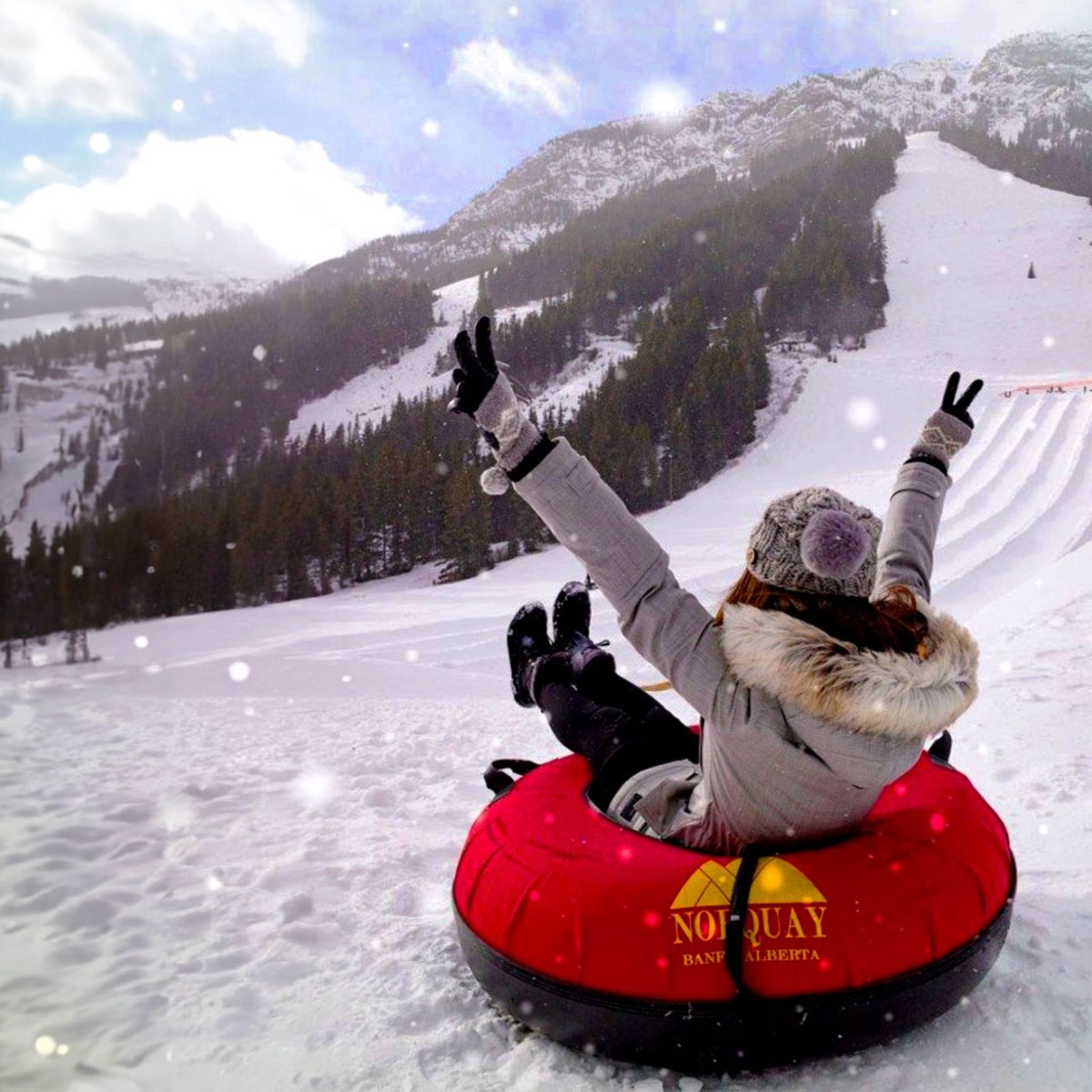 Image shows woman on a red inner tube sliding down a mountain in the snow.