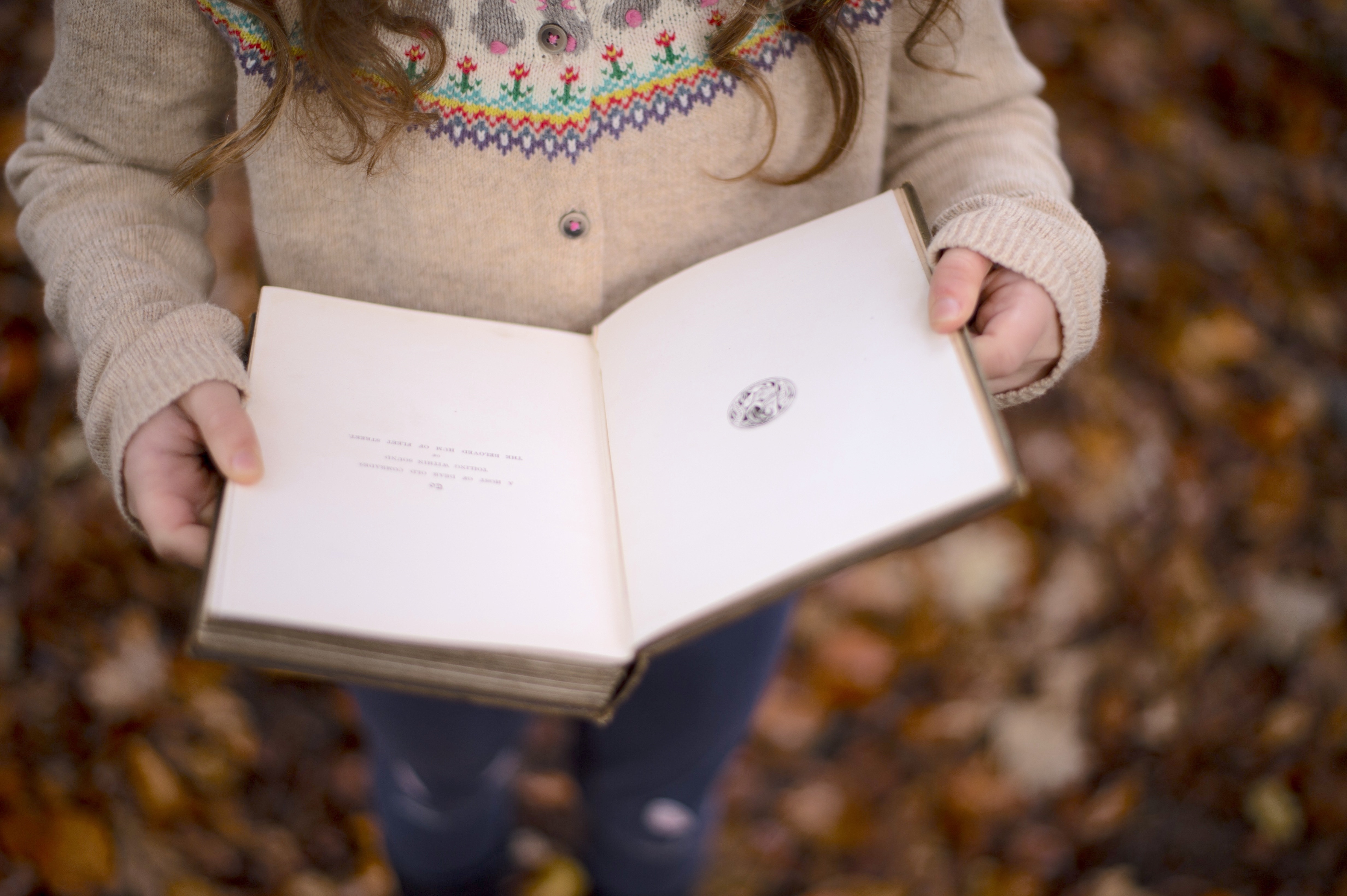 young child wearing a sweater and holding a book