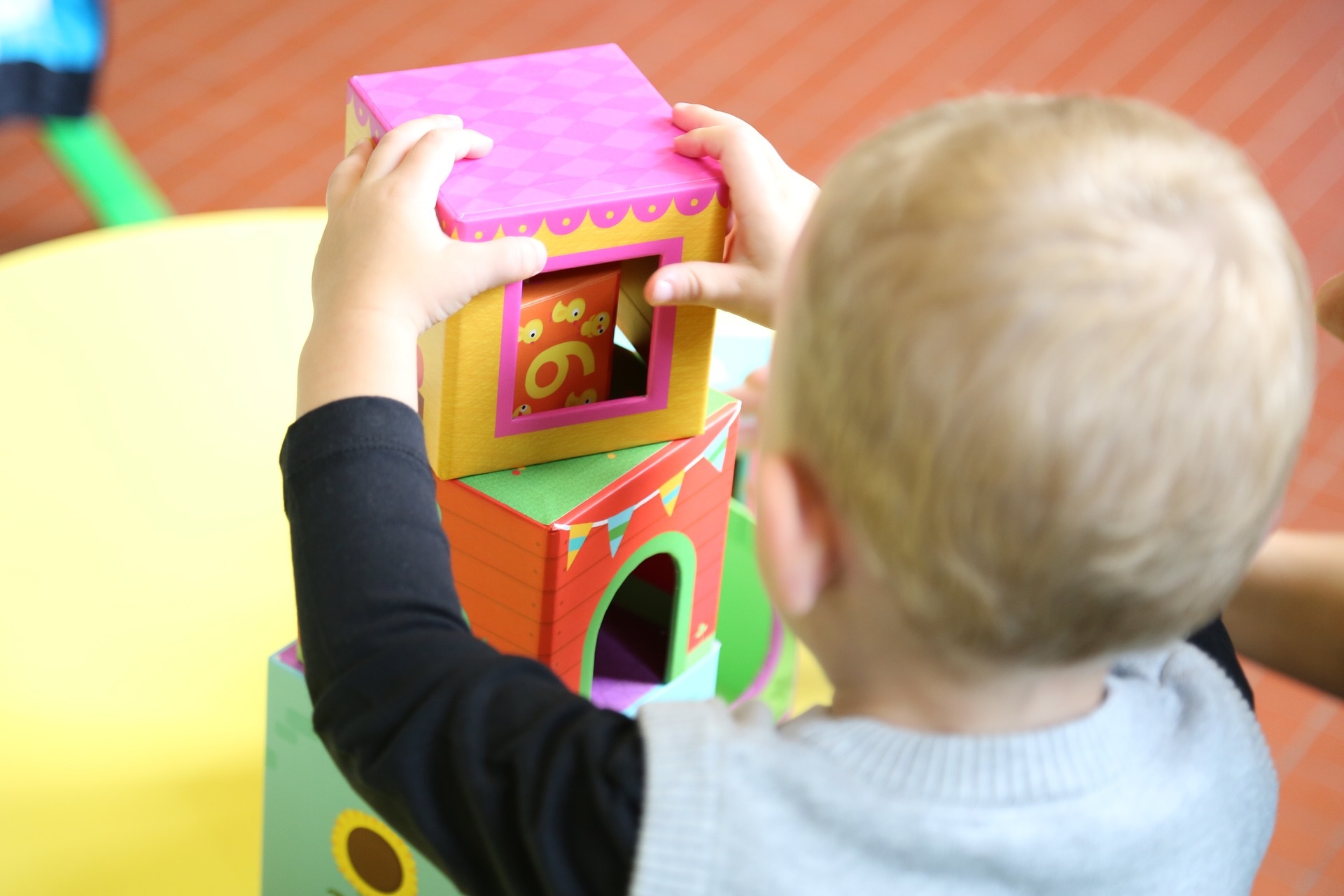 View of back of toddler stacking colorful blocks