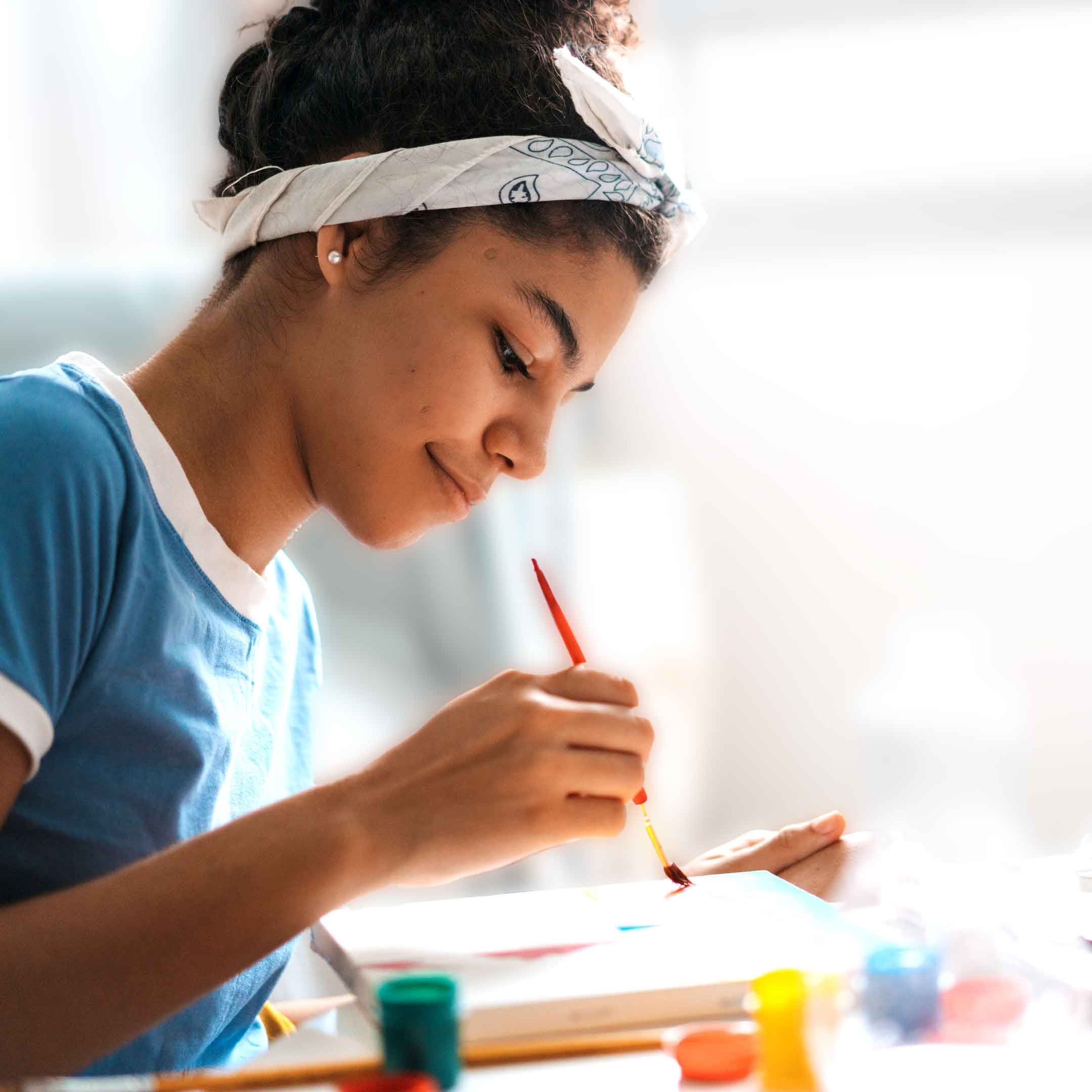 Teen-Paint-Hangout-happy-teen-girl-painting-on-a-canvas-with-acrylic-paints