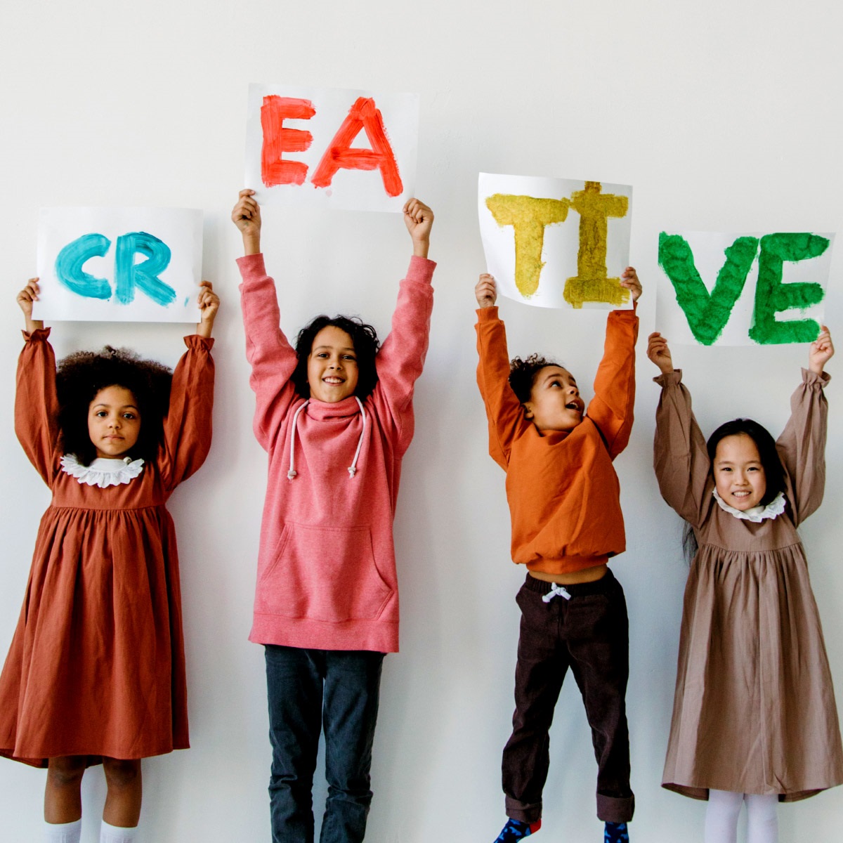 Kids holding up signs that spell out CREATIVE