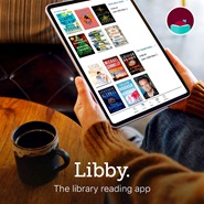 Image depicts a person in a sweater using the Libby App on their ipad.  There is a cup of maybe tea on the table near them.