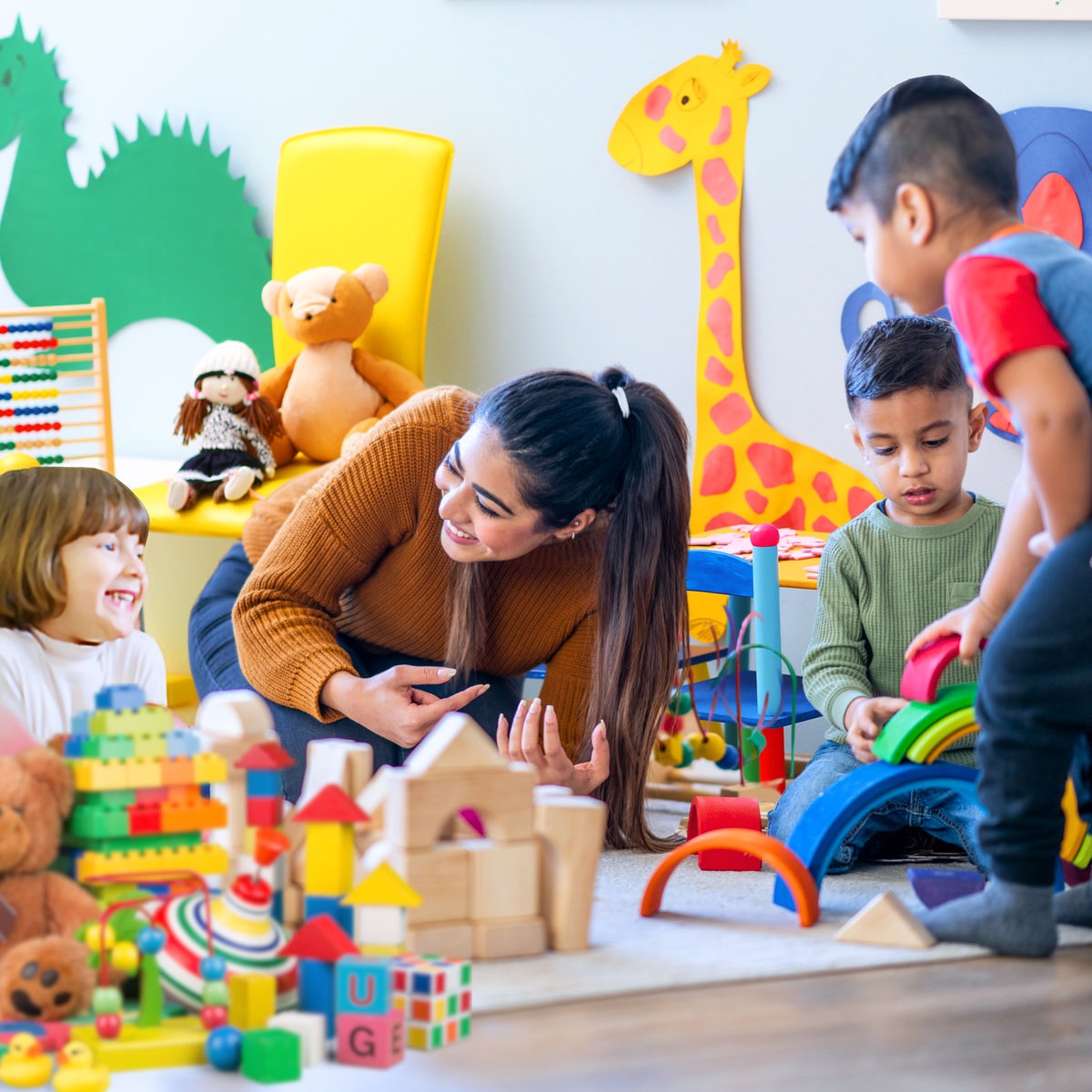 preschool children and an adult play with colorful toys on the floor