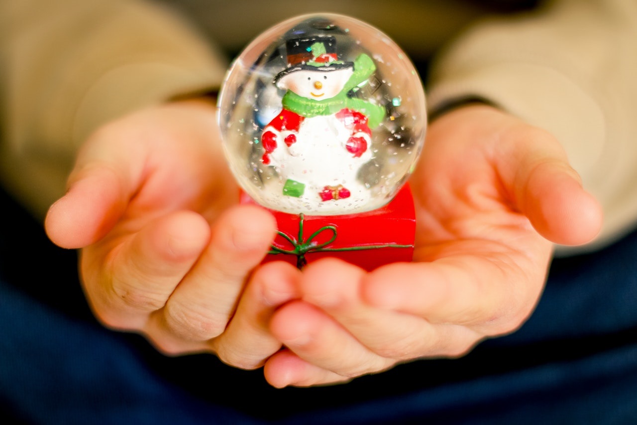 hands holds a small holiday snow globe