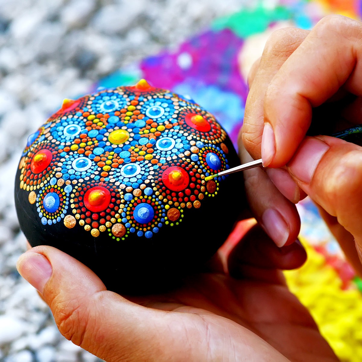 a rock is being painted in elaborate design.