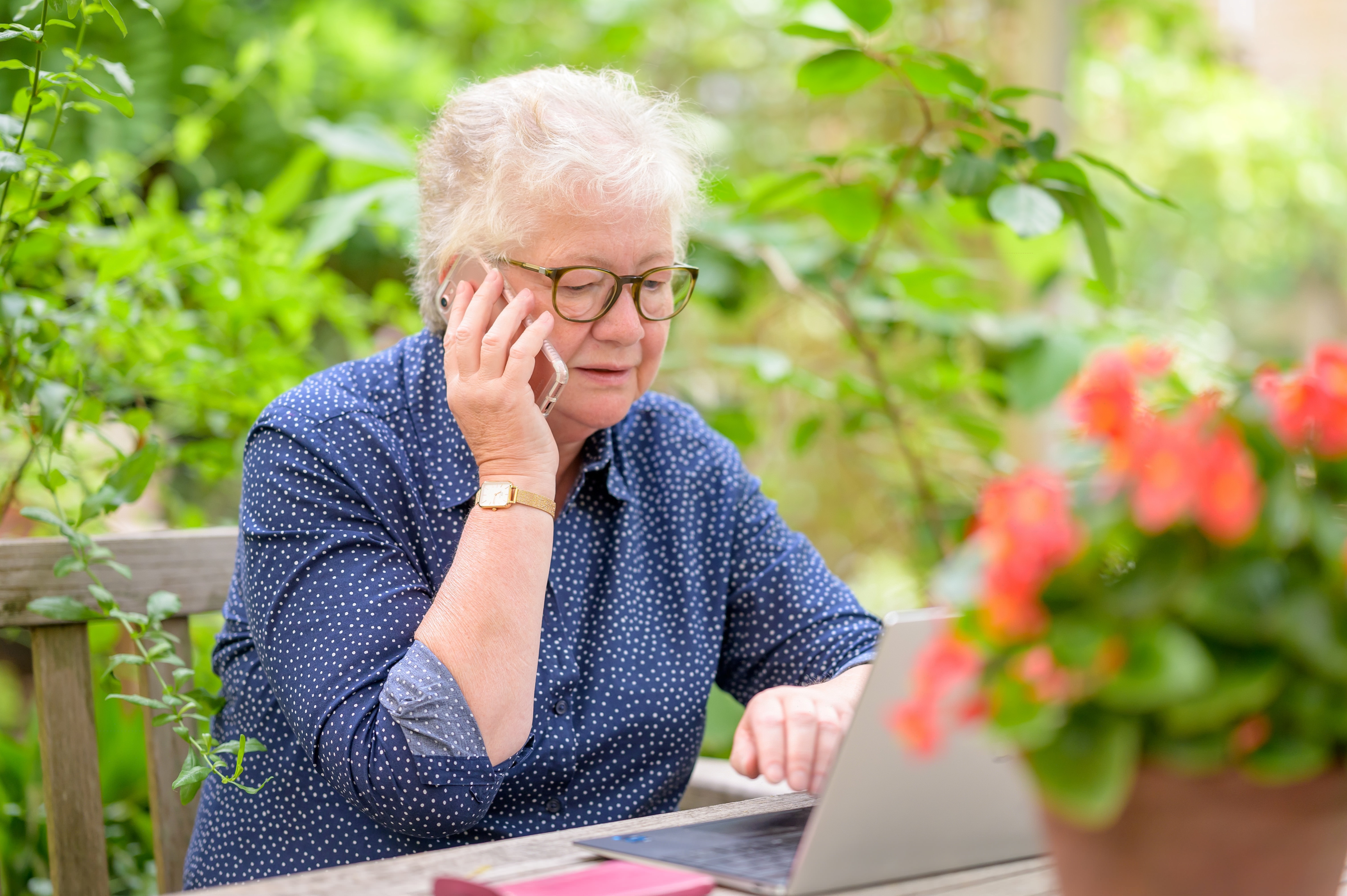 Woman Talking on Smartphone While Using Laptop Outdoors